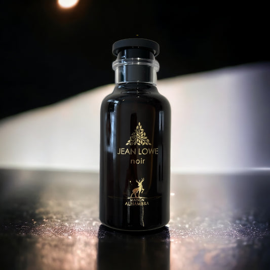 Flacon de parfum élégant et sophistiqué, en verre noir brillant reflétant subtilement la lumière. L’étiquette dorée affiche le nom 'JEAN LOWE noir' accompagné du logo distinctif de la marque 'Al Haramain'. Le bouchon cylindrique noir avec une bague transparente ajoute une touche moderne au design classique. Posé sur une surface sombre légèrement texturée, le flacon est mis en valeur par un éclairage tamisé et un arrière-plan flou, créant une ambiance mystérieuse et luxueuse.